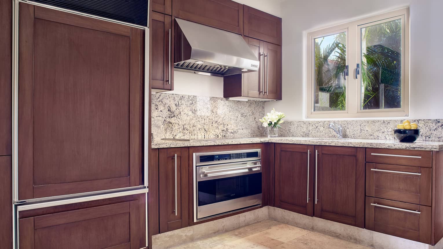 Arena Beach House kitchen with wood cabinetry, marble countertops, window
