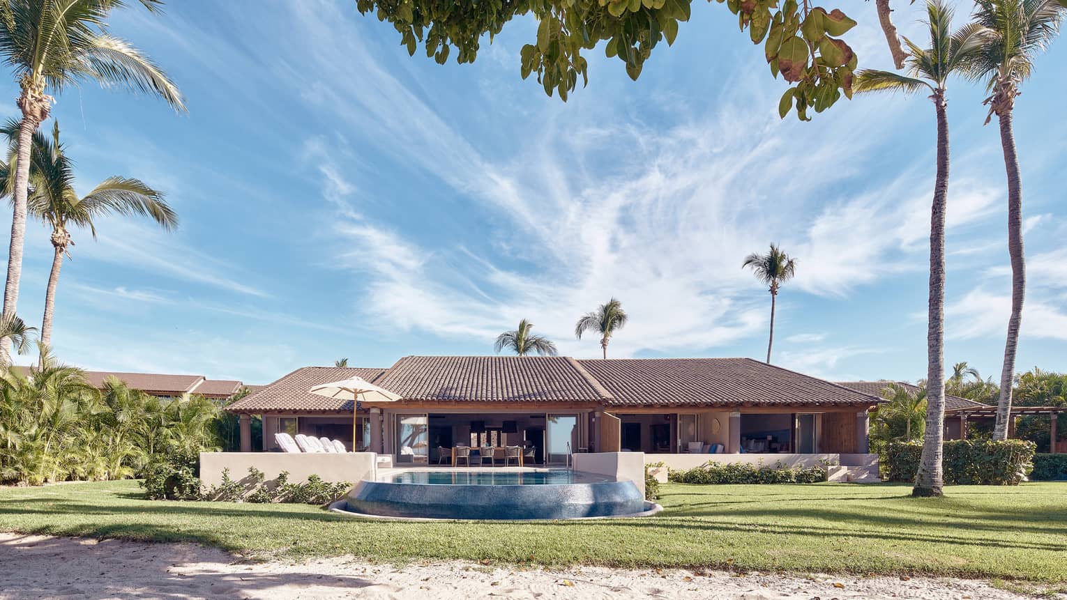 Arena Beach House exterior with palm trees and pool