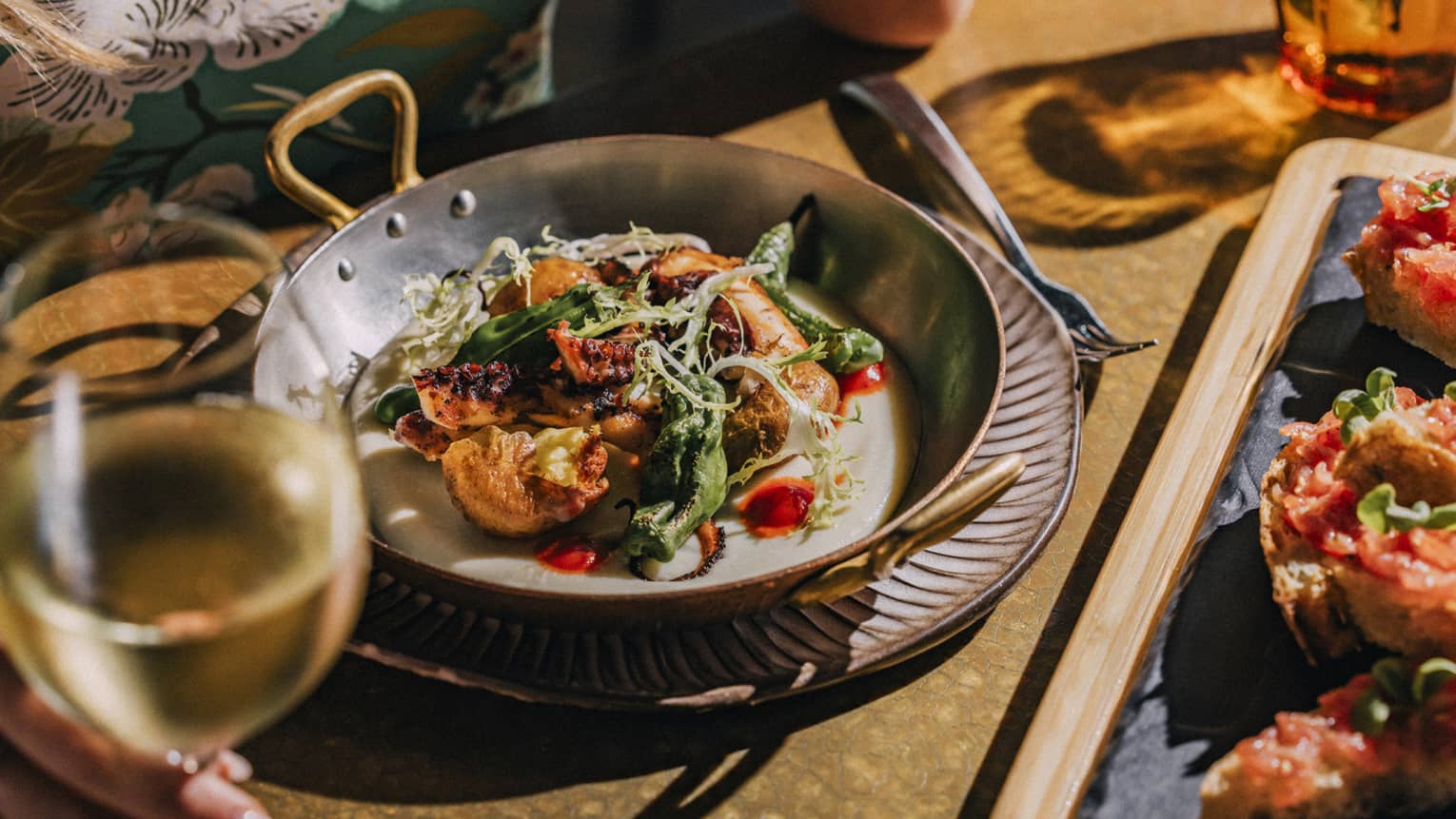 Grilled Spanish Octopus dish with glass of white wine