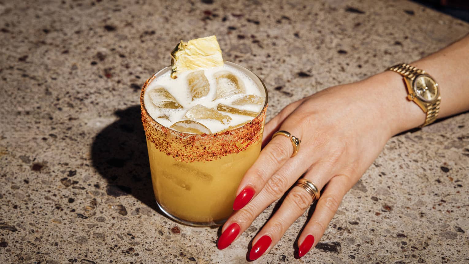 Pisco cocktail and woman's hand with red nail polish