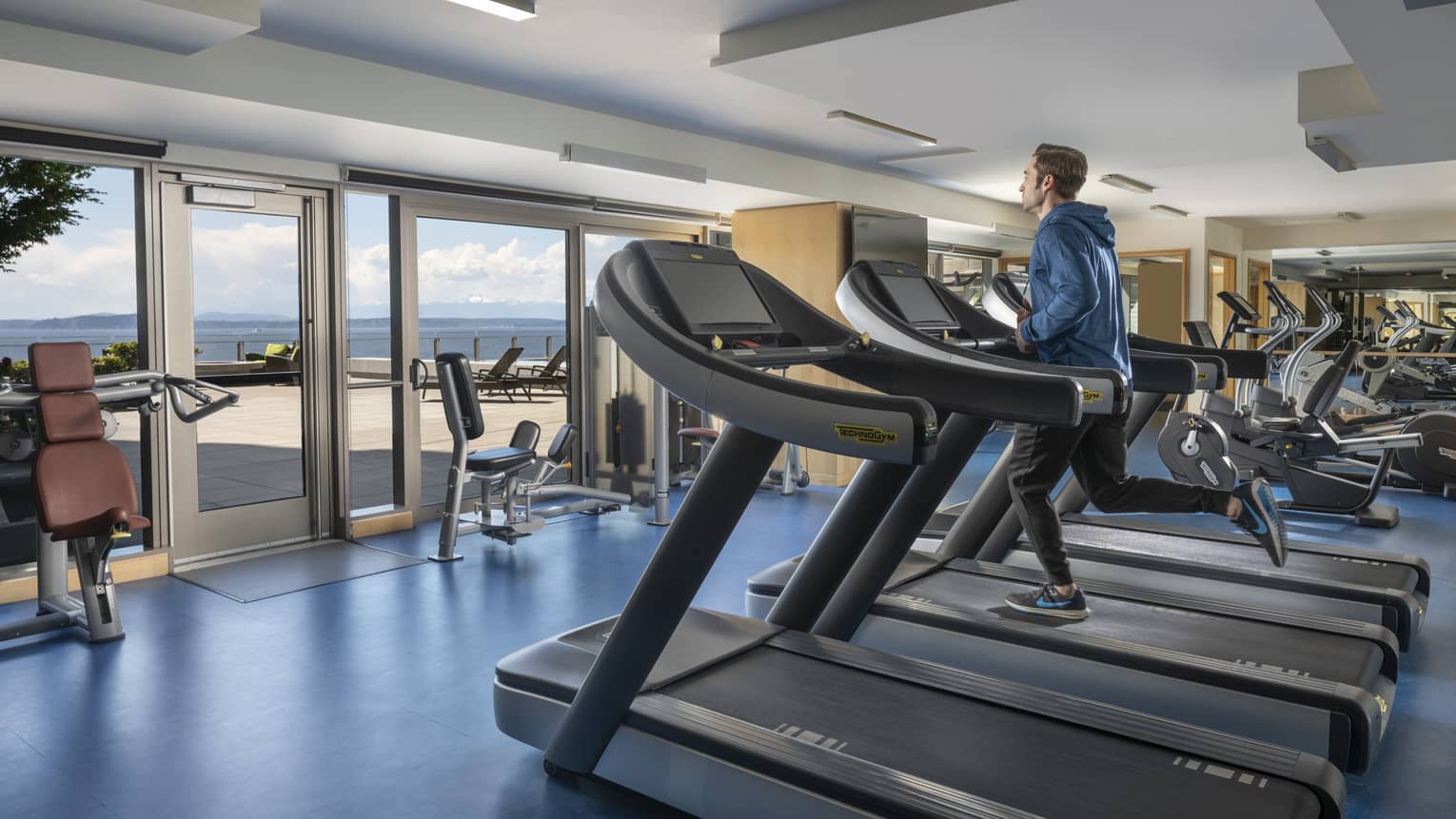 A man runs on a treadmill in an elaborate fitness center