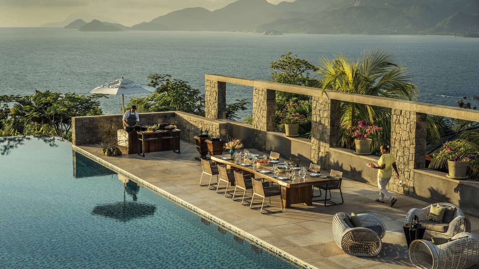 Aerial view of Four-Bedroom Residence Villa private deck with 8-person dining table beside pool, ocean view