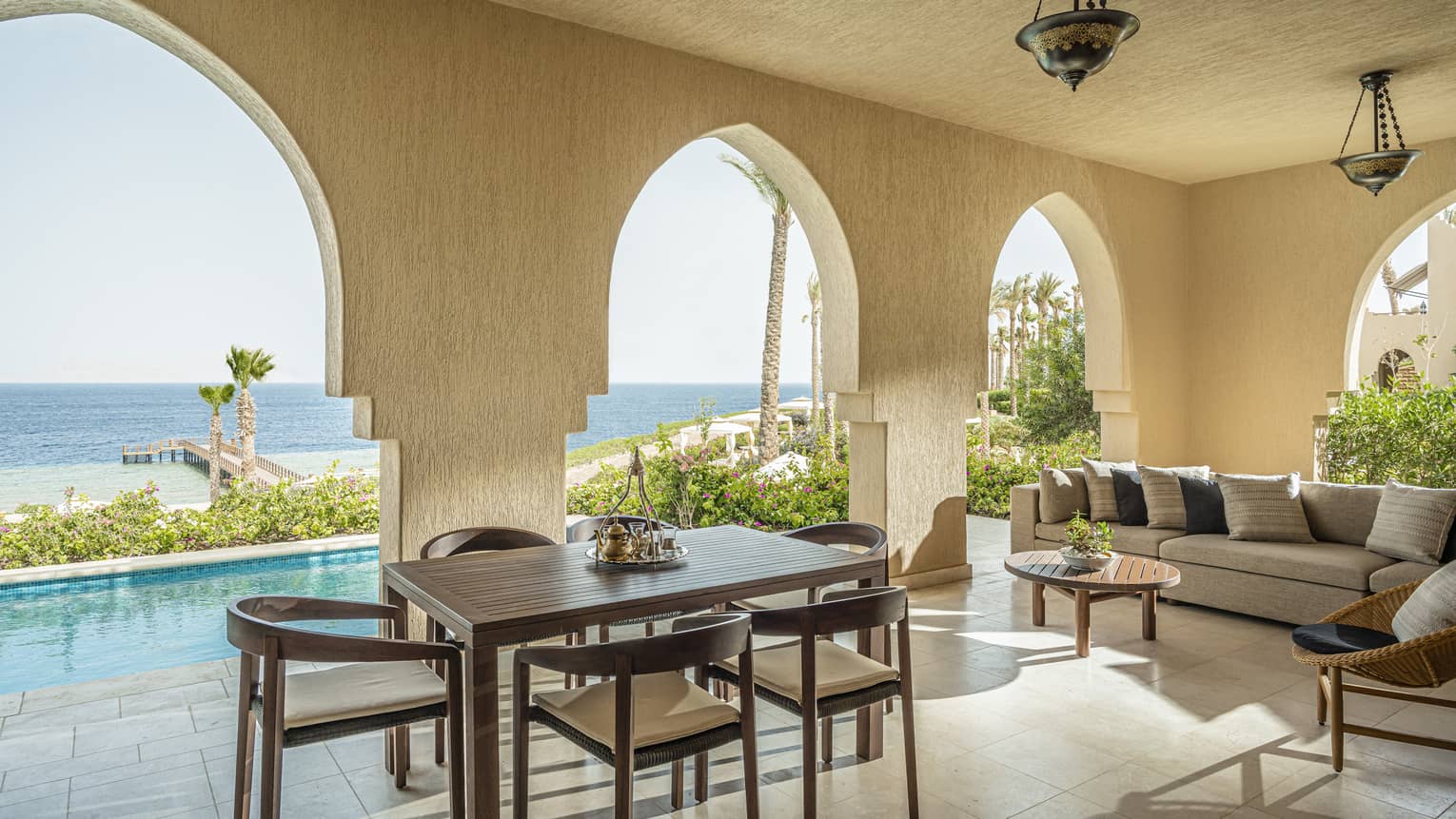 Imperial Suite terrace with cafe table, cream sectional sofa, archway leading to pool, views of the Red Sea
