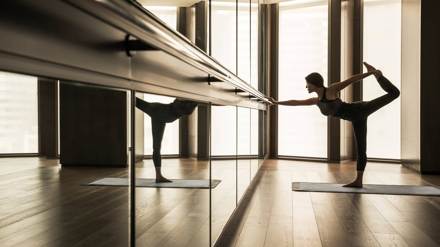 Woman stretching leg behind her while touching bar in fitness studio