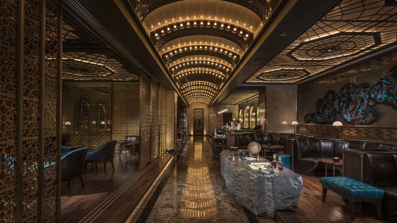 Dimly lit Charles H Bar lounge with stone table, leather banquettes, arched lights 