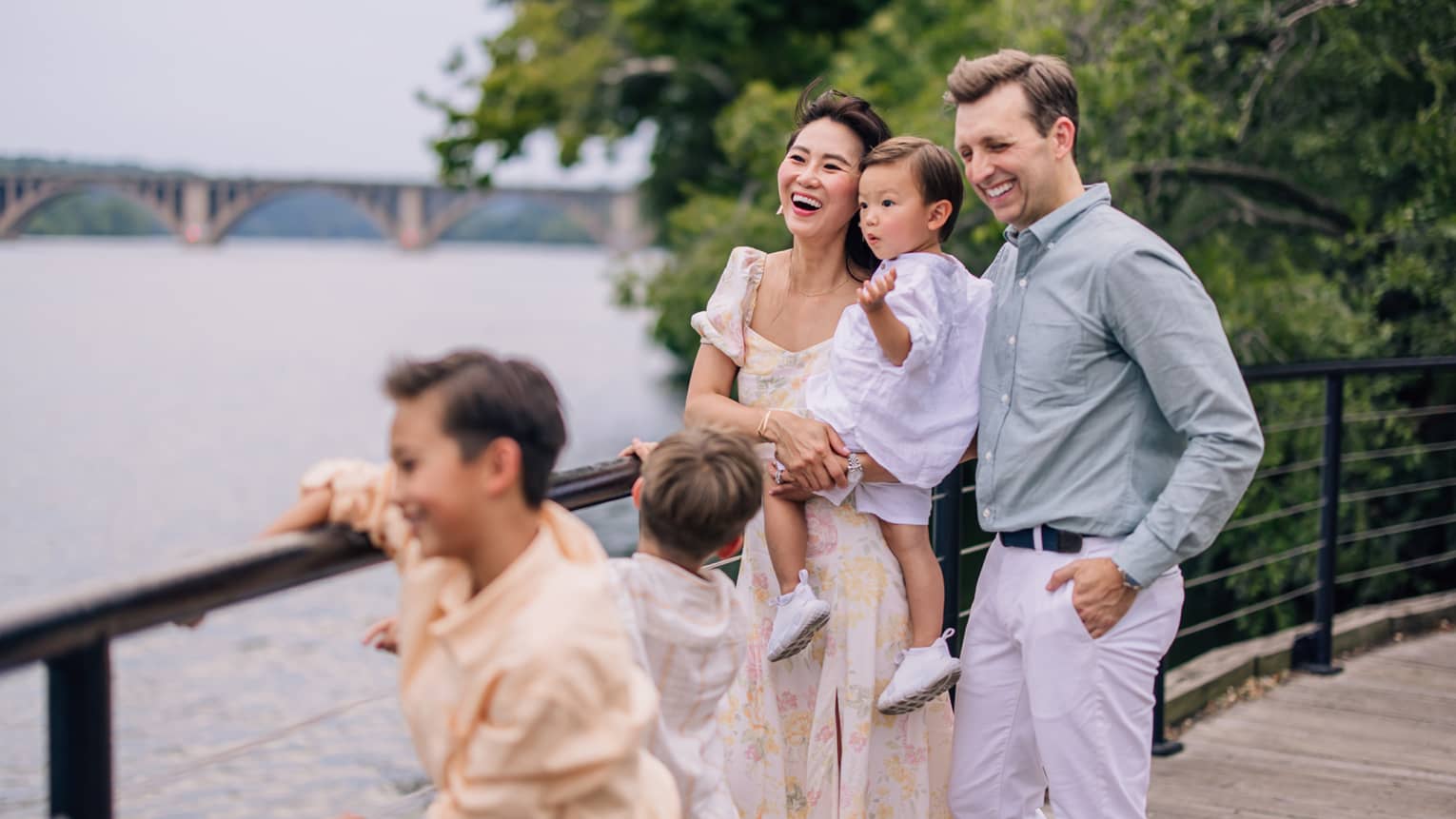 A man, woman, and three young children smile on a waterside path