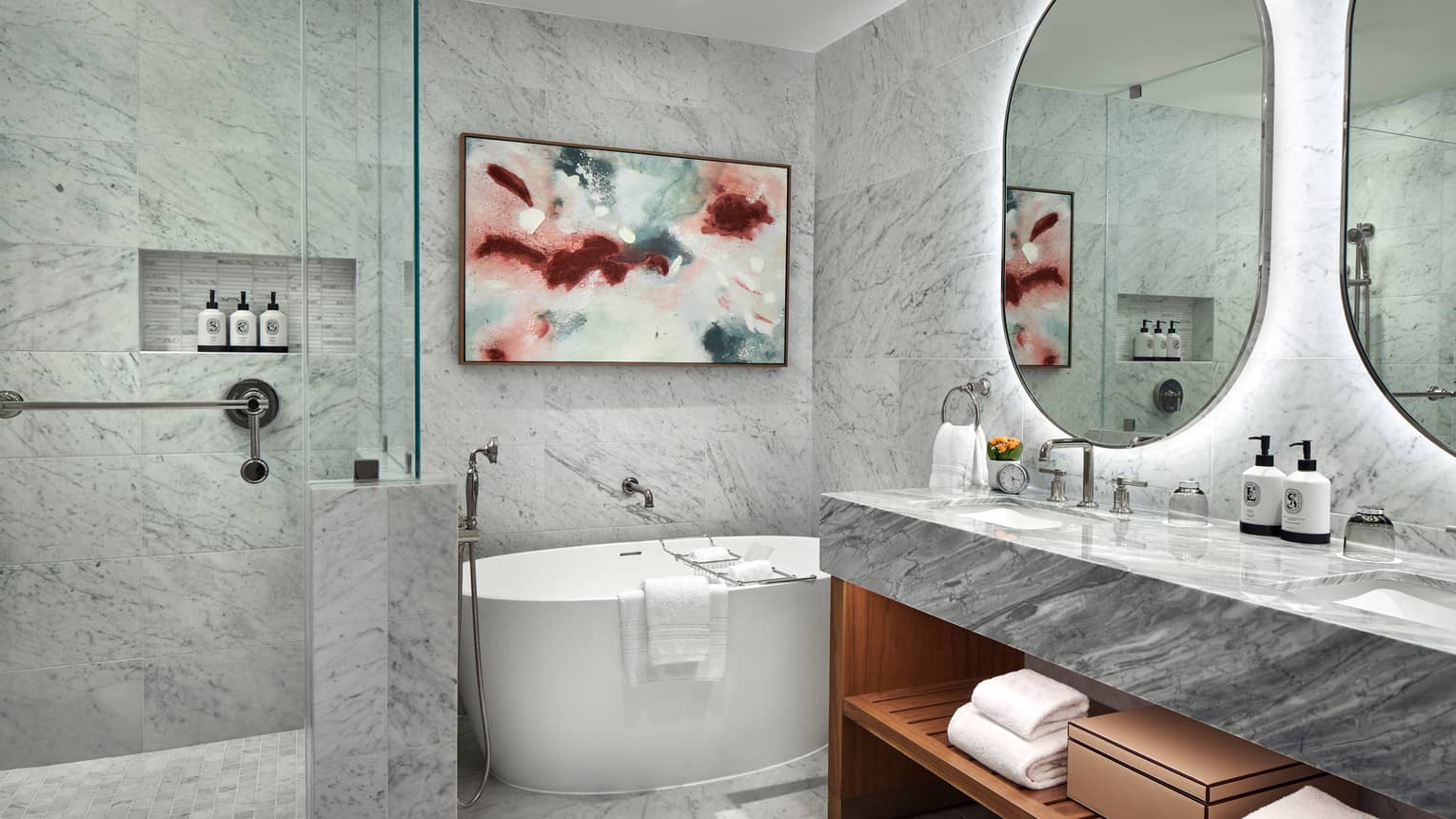 Marble bathroom with standalone tub and walk-in shower, as well as an illuminated double vanity
