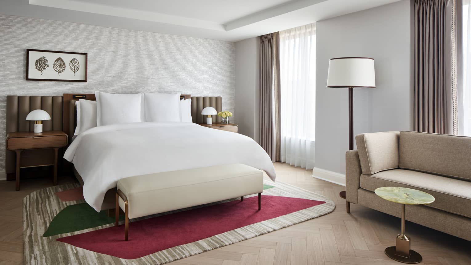 Elegant hotel room featuring a king bed, chaise with small table, and two bedside tables