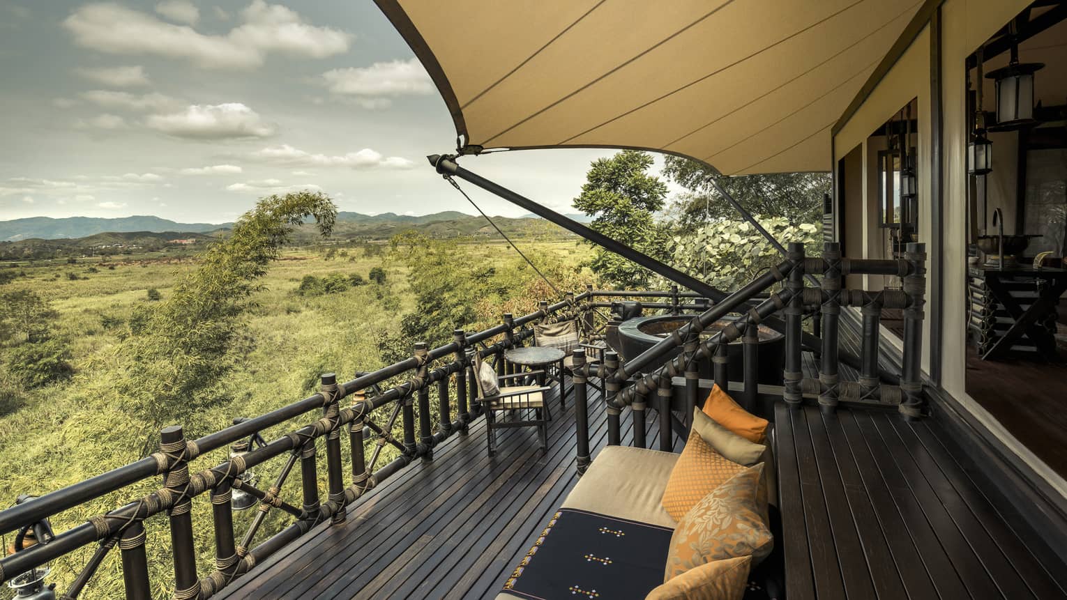 View from balcony of luxury tent: breathtaking scenery, lush greenery, and a clear blue sky.