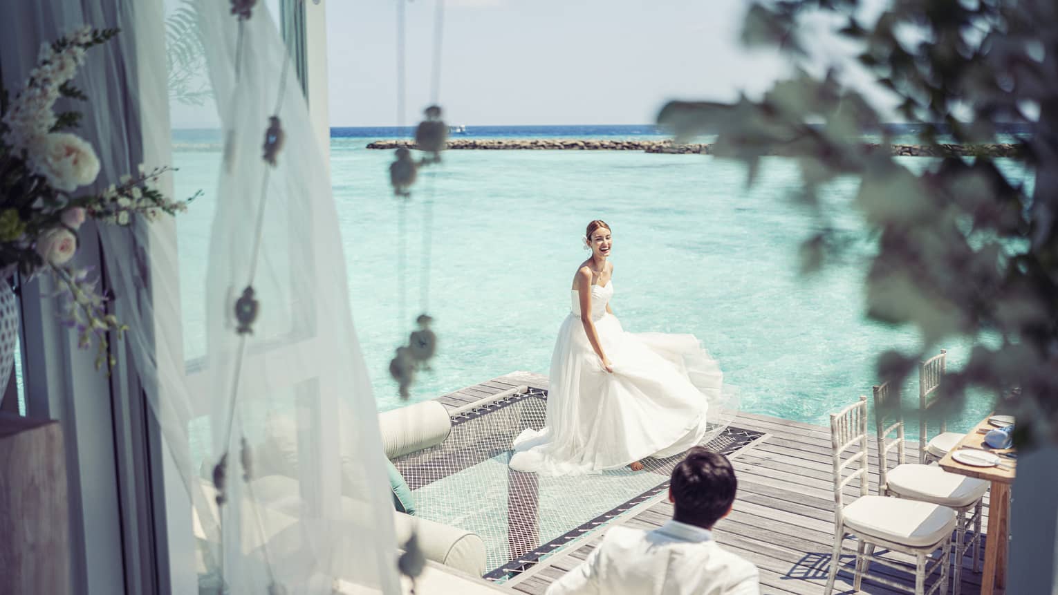 Bride and groom relax before their reception in their overwater wedding bungalow with glass-bottom floor