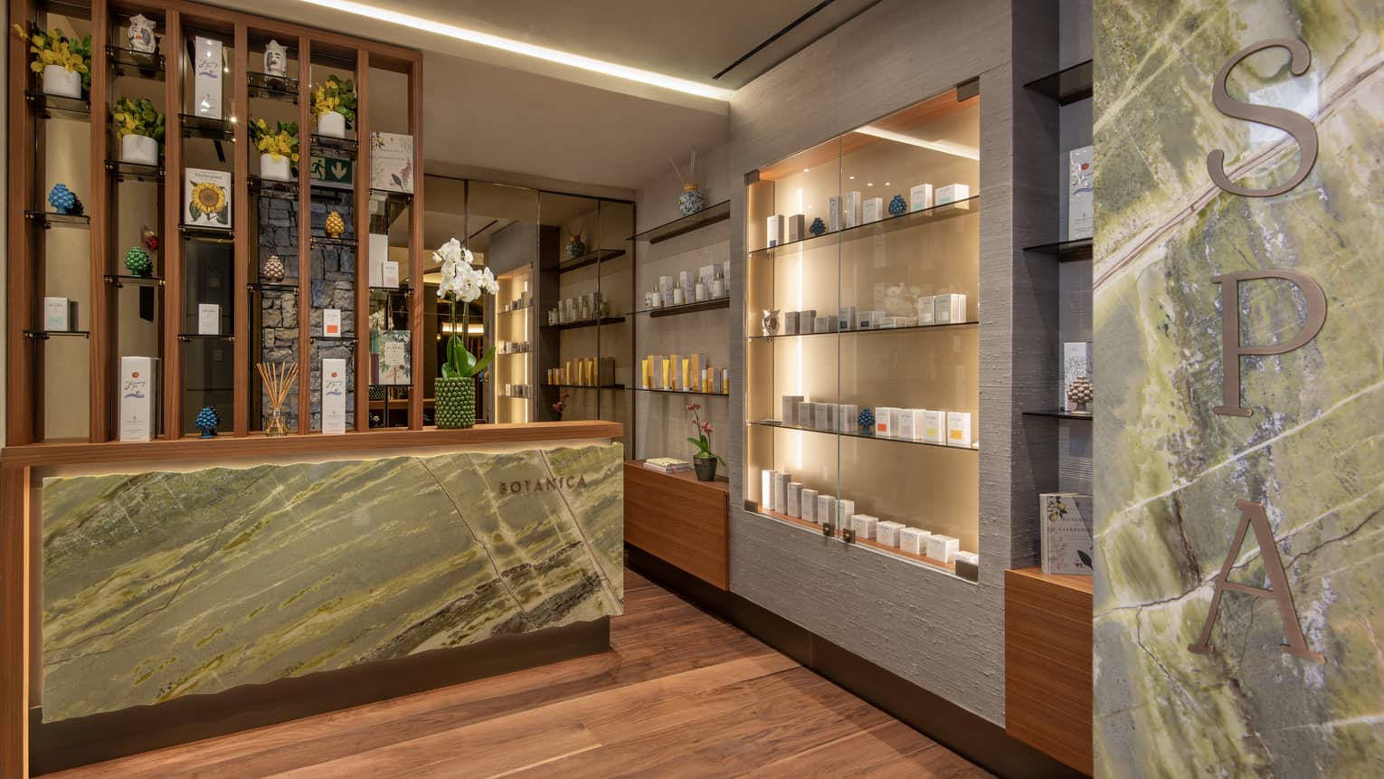 Spa reception area with marble desk and uplit wall with retail spa products