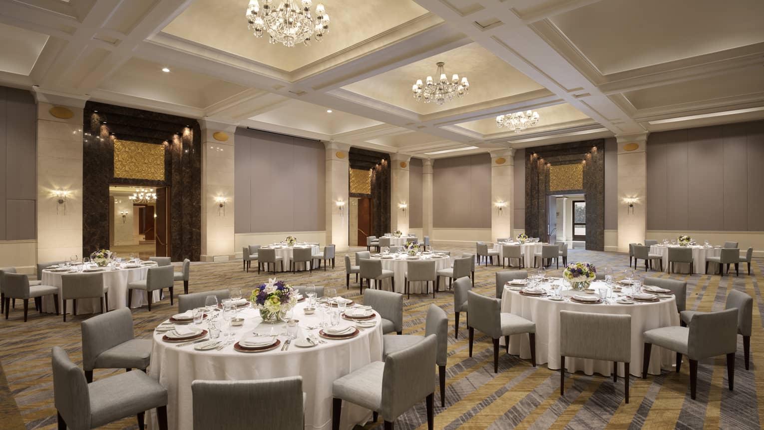 Several round tables set with white table clothes and square chairs.