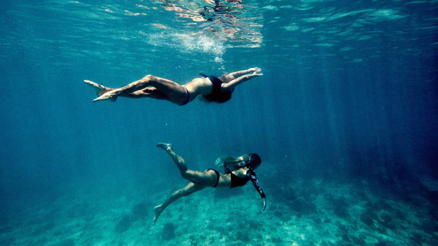 Underwater view of two women swimming in ocean