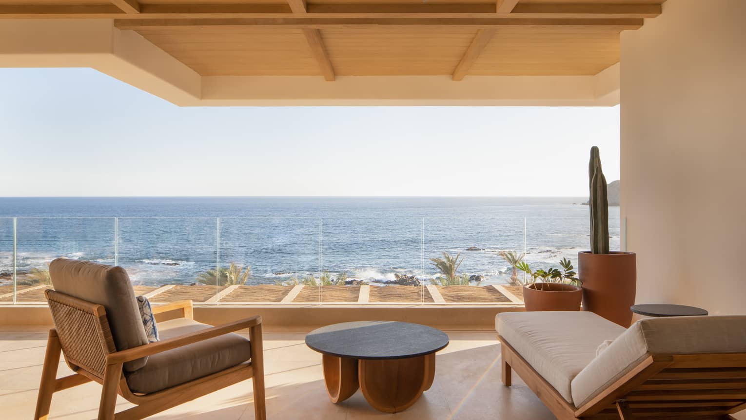 Covered terrace with sun lounge r and arm chair, overlooking the sea