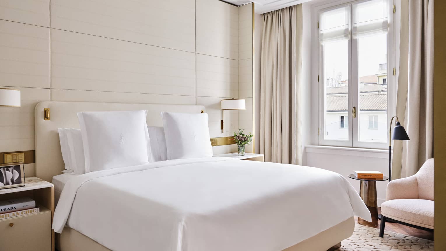 Contemporary hotel room with a king bed and light pink arm chair by the window