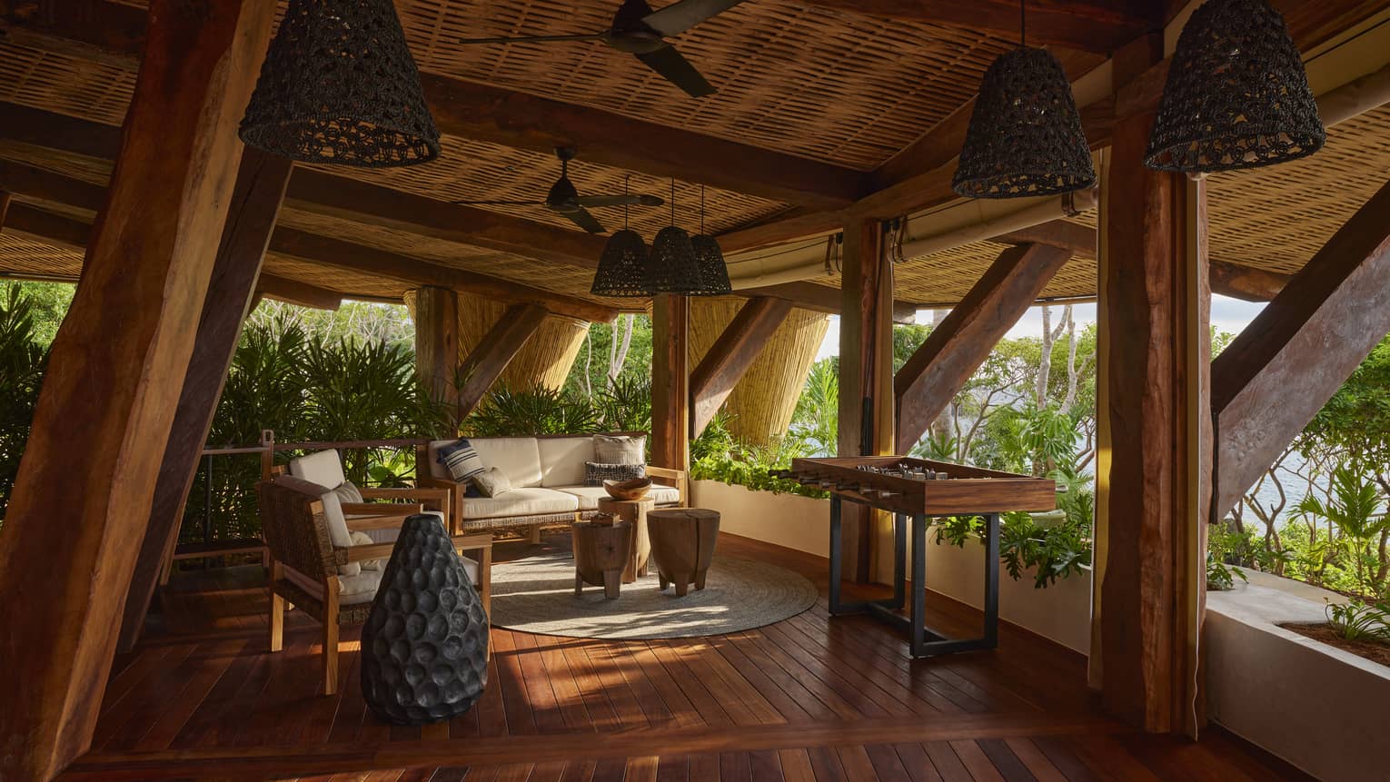 Copal restaurant living room, with wooden beams holding roof, with opening to the tropical forest
