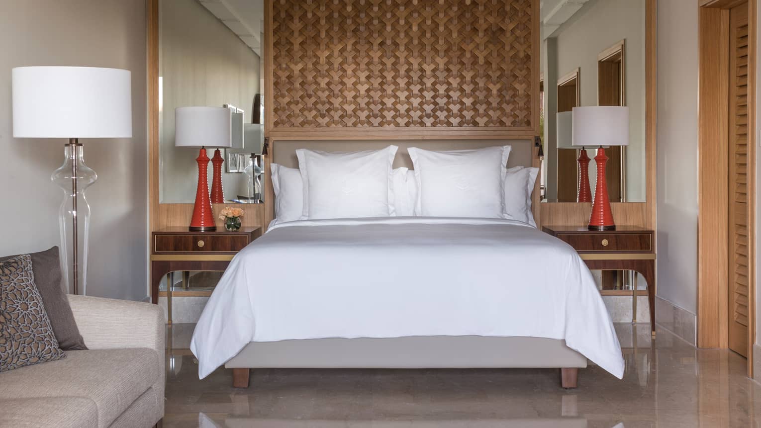 Deluxe Room bed under lattice wood panel, red lamps on nightstands