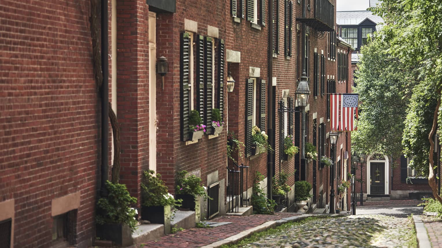 A cobblestone alley in Beacon Hill, lined with red brick residential buildings 