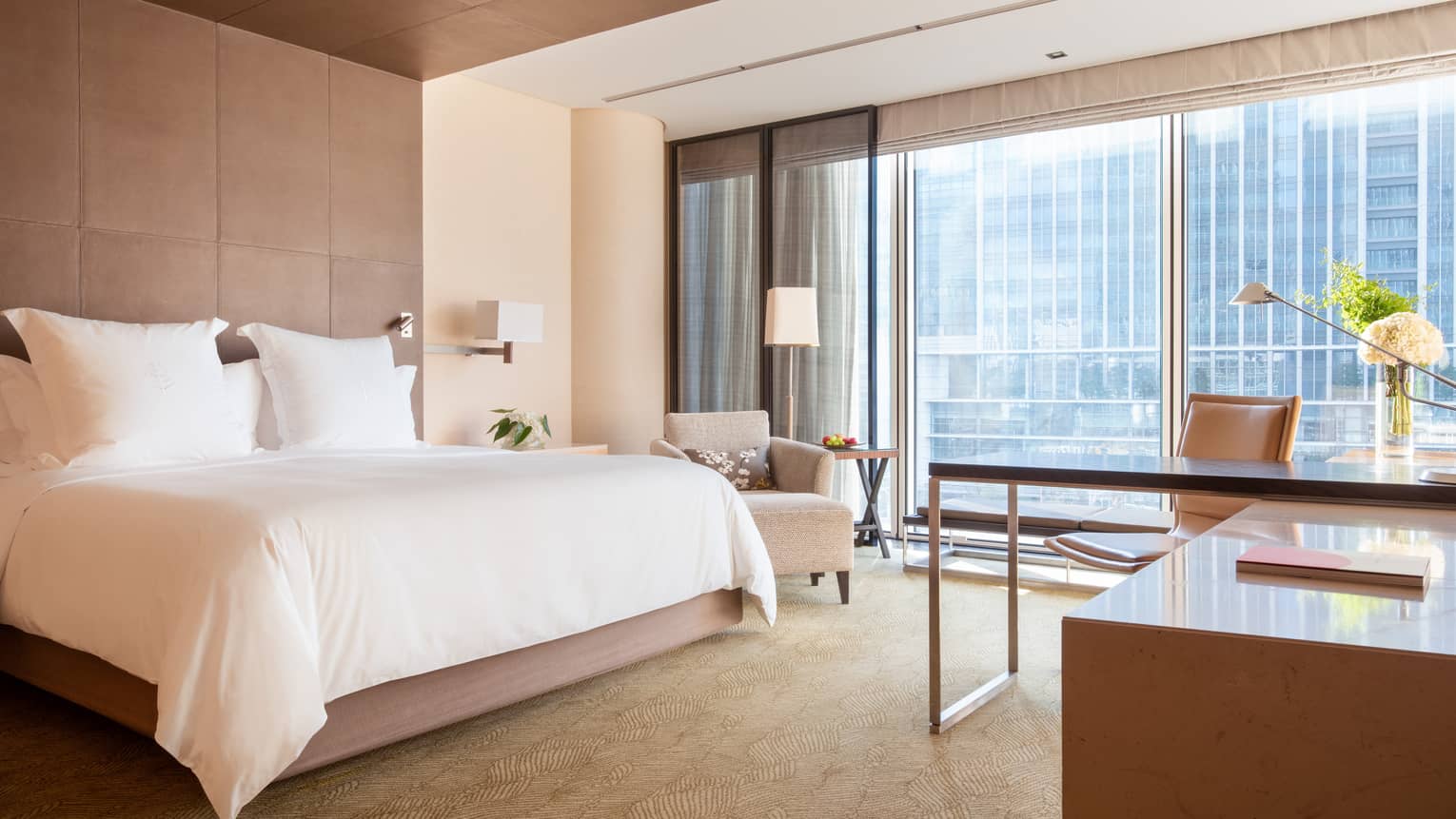 Deluxe City View Room with floor-to-ceiling windows looking out onto the skyline and a desk area