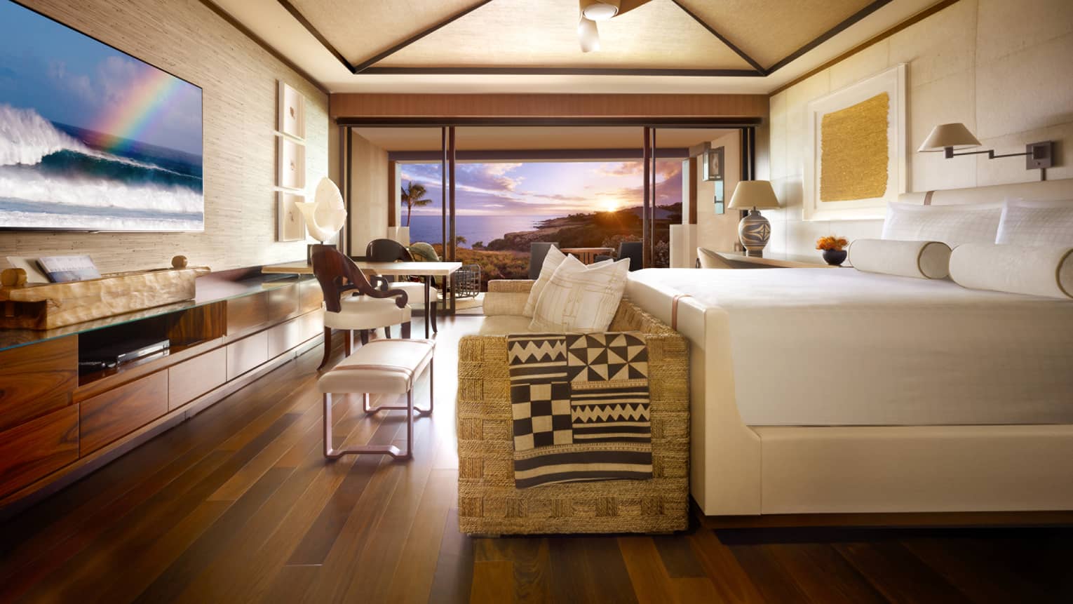 Partial Ocean-View Room bed, wicker sofa at foot with throw blanket, TV screen displaying waves, rainbow