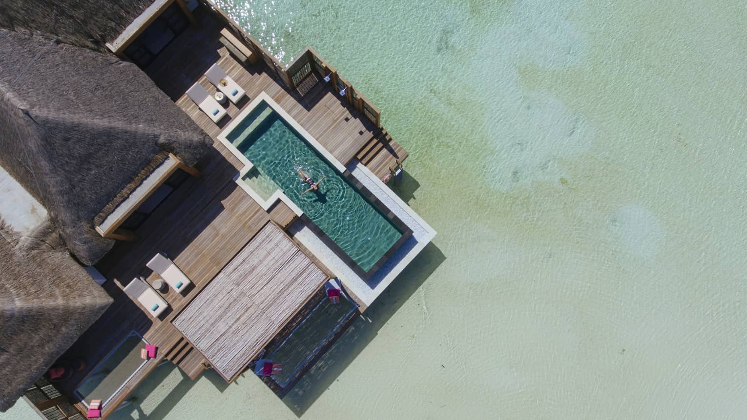 Aerial view of water suite, woman floats on back in private pool
