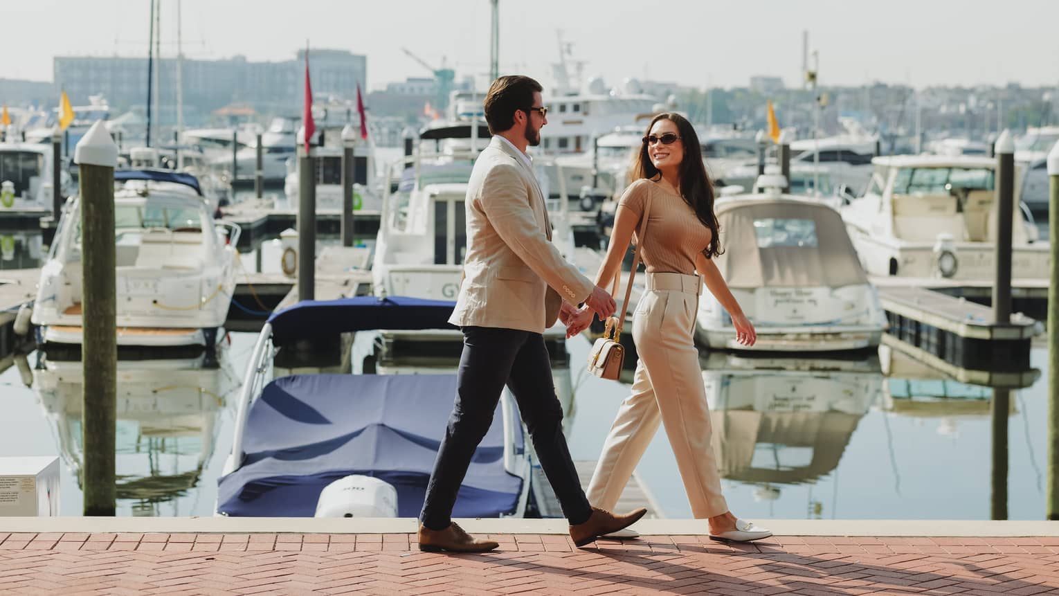 Two guests walking together near a waterfront with boats in the water