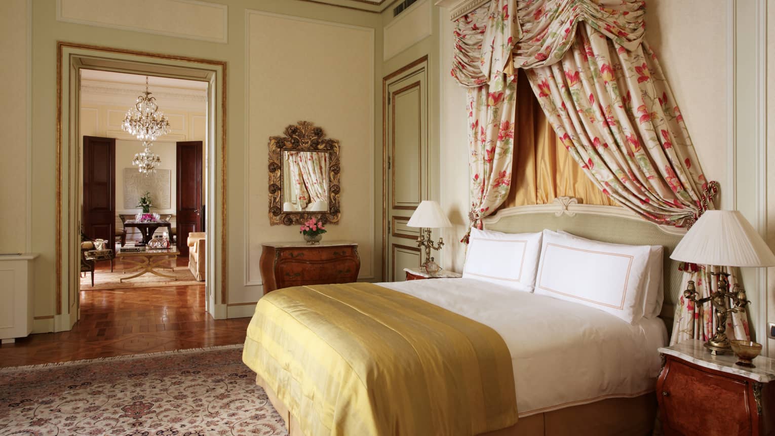 La Mansión Presidential Suite bed with gold blanket, floral drapes above headboard, door to dining room