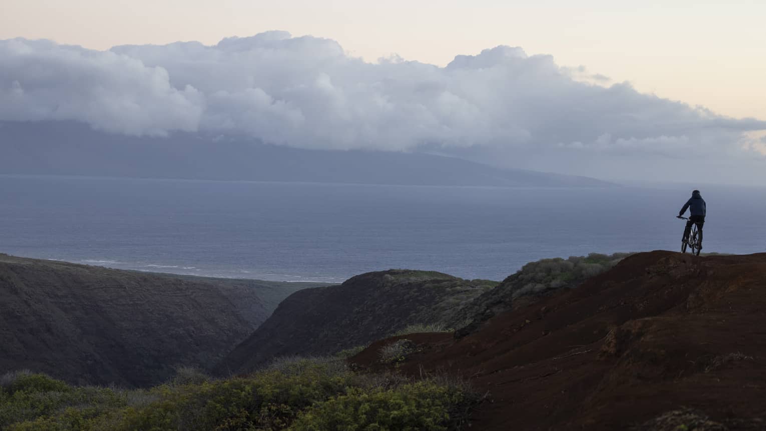 A person rides mountain bike on rugged, tropical terrain