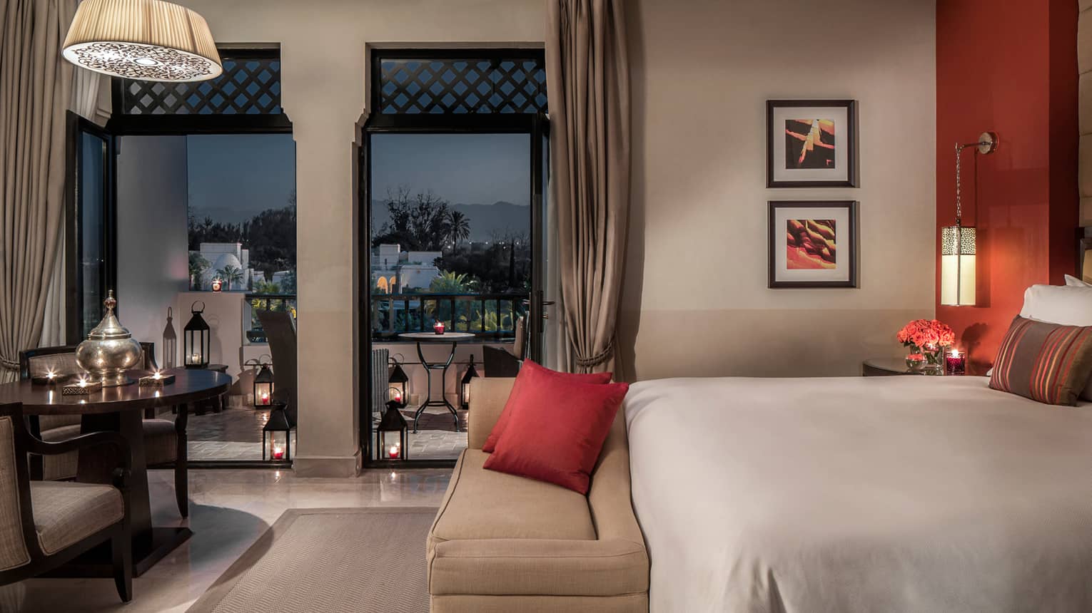 Pool Terrace Room at night with bed, plush bench, candle-lit table and lanterns on patio