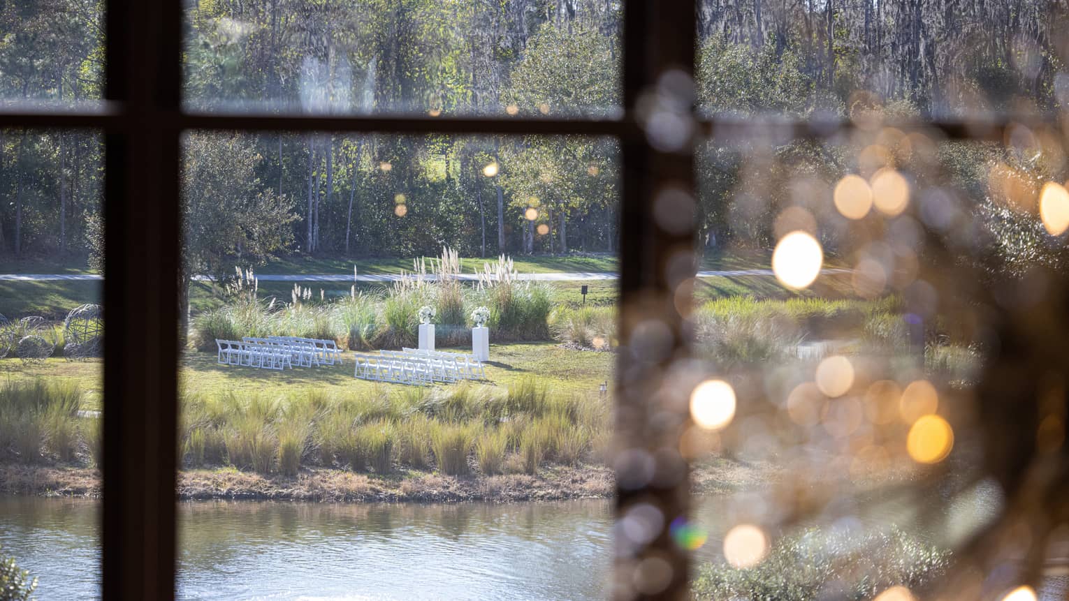 View through a large window looking out onto a wedding set up on a lawn