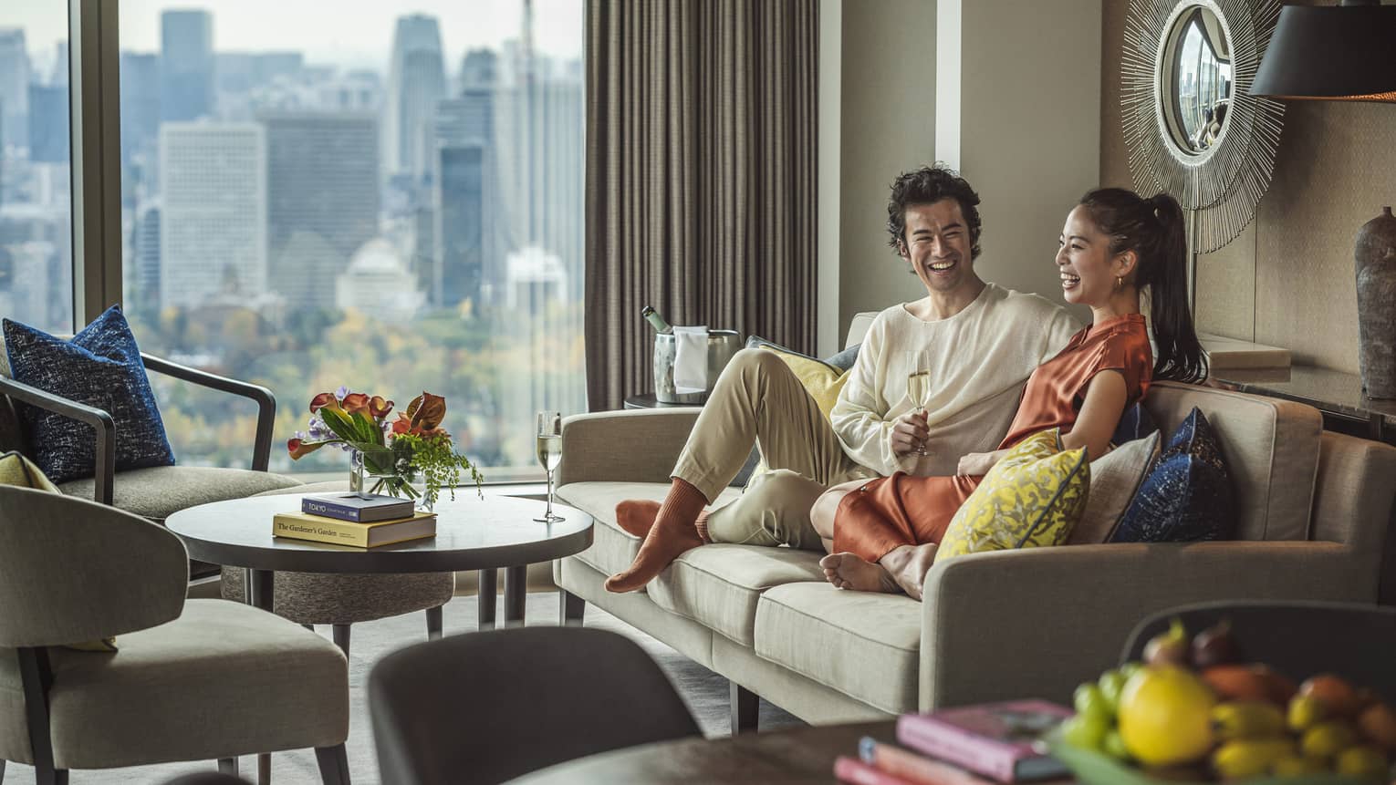 Two people sitting on a sofa, smiling and enjoying a drink together