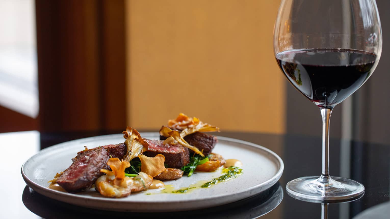 Steak dinner with caramelized chanterelle mushrooms and garlic herb butter, glass of wine