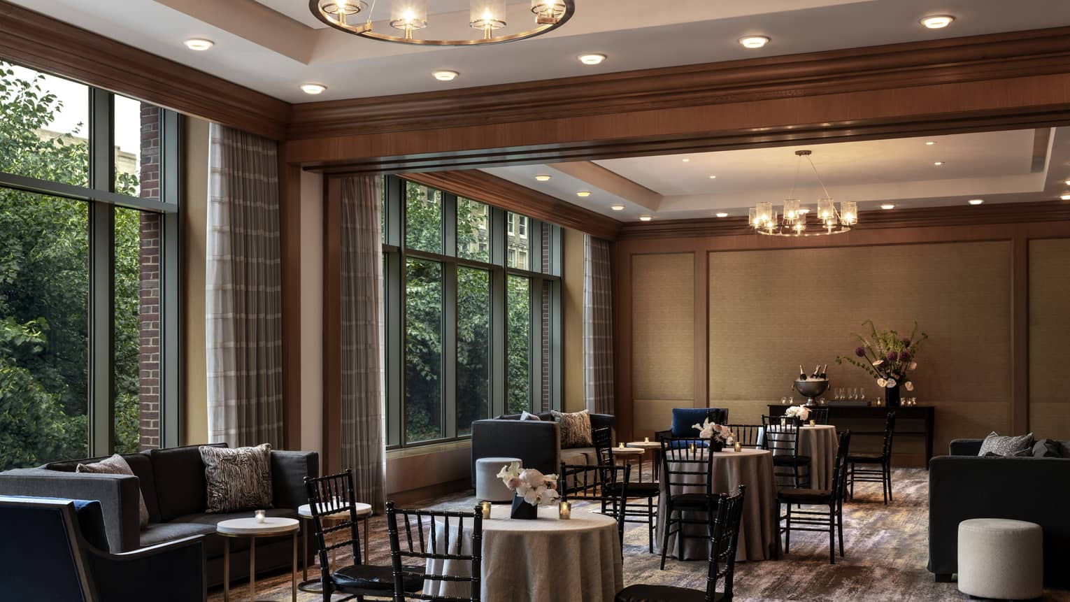 A  dimly lit seating area with black chairs around small tables and small black sofas.