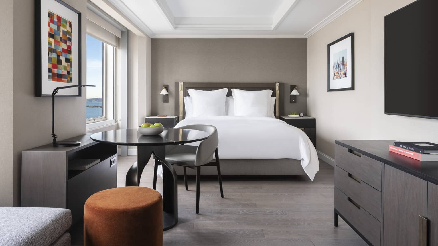 Hotel room featuring a Four Seasons queen bed, a small table with a chair, and a sofa