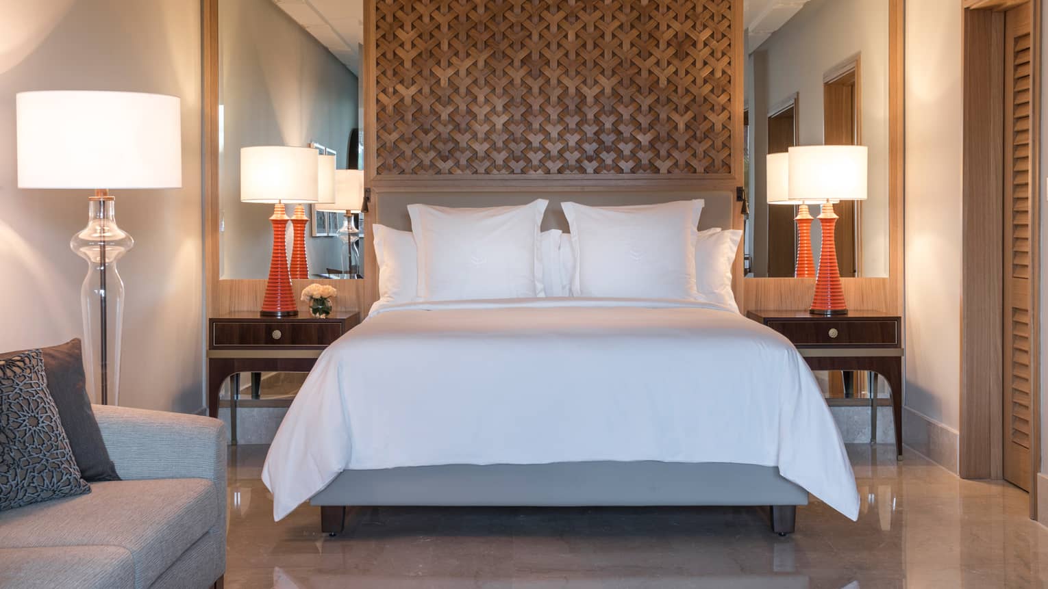 Superior Room bed under lattice wood panel, red lamps on nightstands, sofas