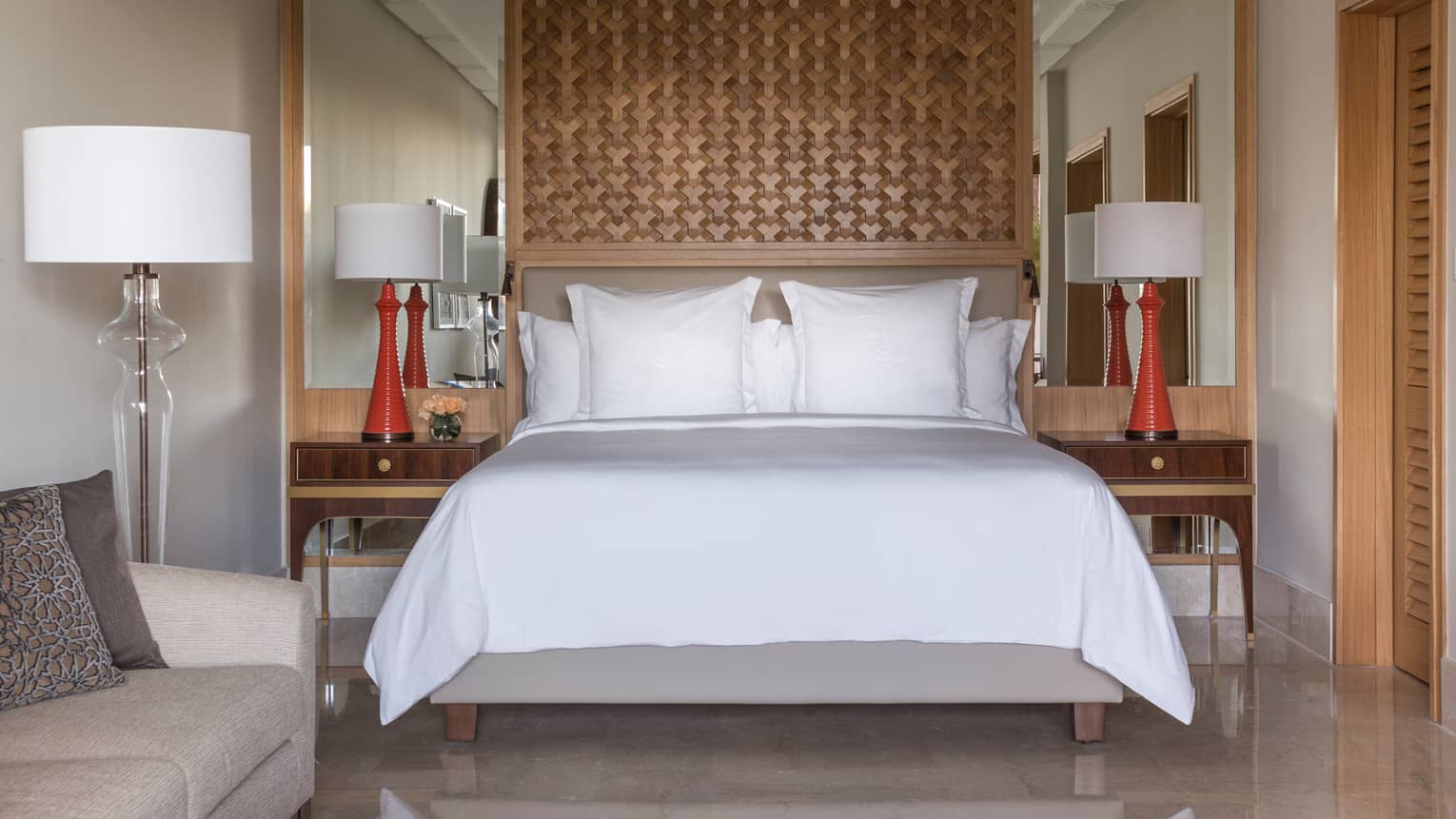Deluxe Room bed under lattice wood panel, red lamps on nightstands
