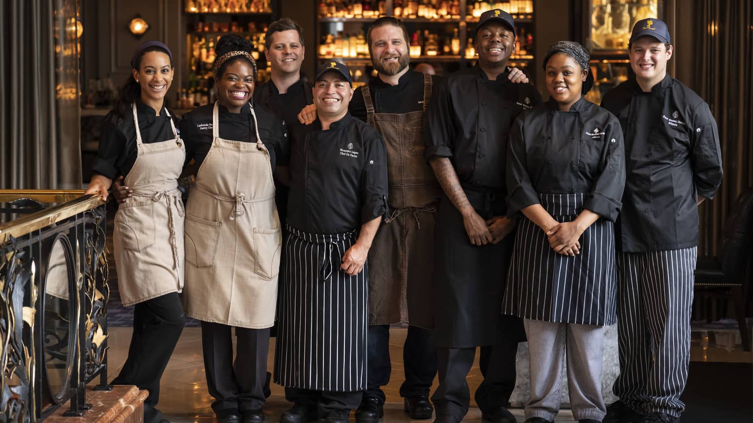 A smiling group of restaurant staff members in aprons