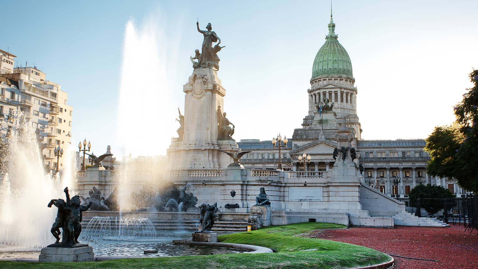 Large fountain, historic building and courtyard on sunny day