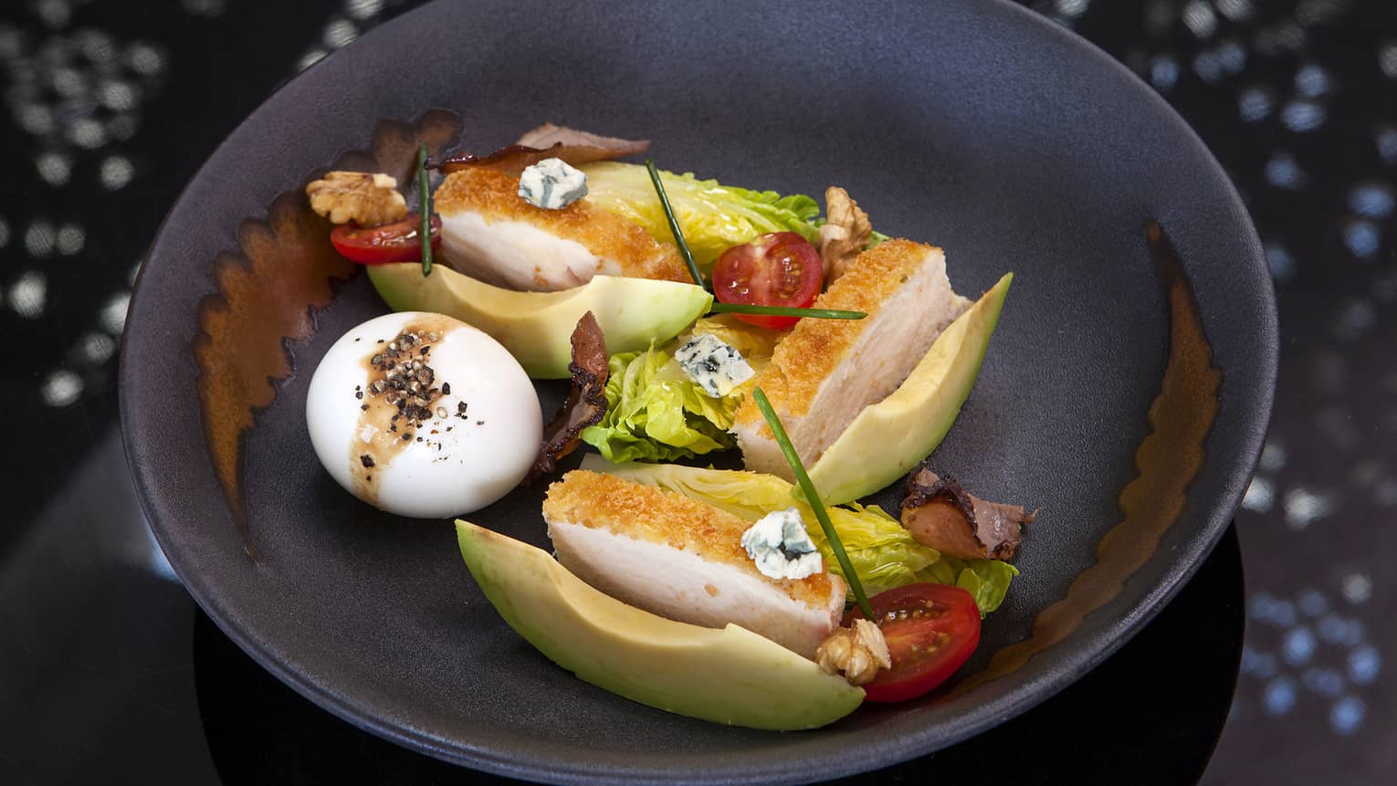 A Cobb Salad with chicken breast, a hardboiled egg, avocado, tomatoes, lettuce and blue cheese