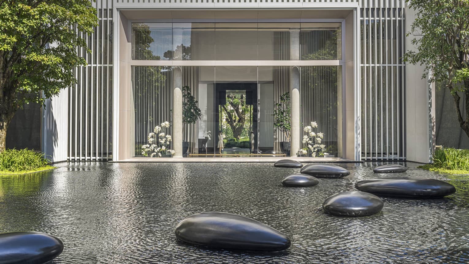 Calm pond in front of hotel with large polished stones scattered throughout