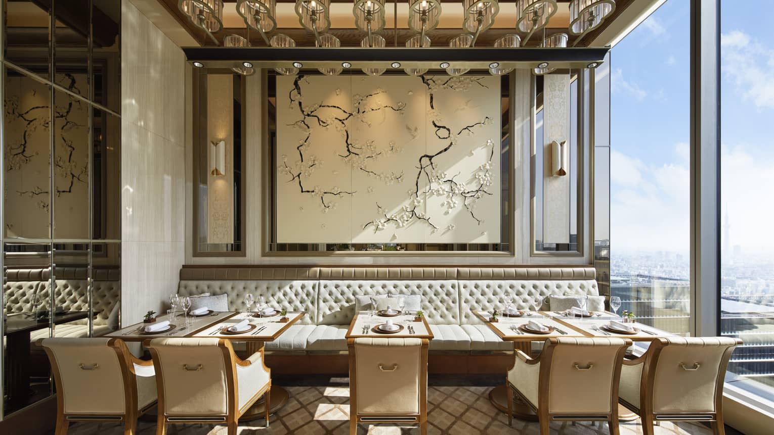 Est dining room with tables for two, muted cream decor, natural light, view of the city 