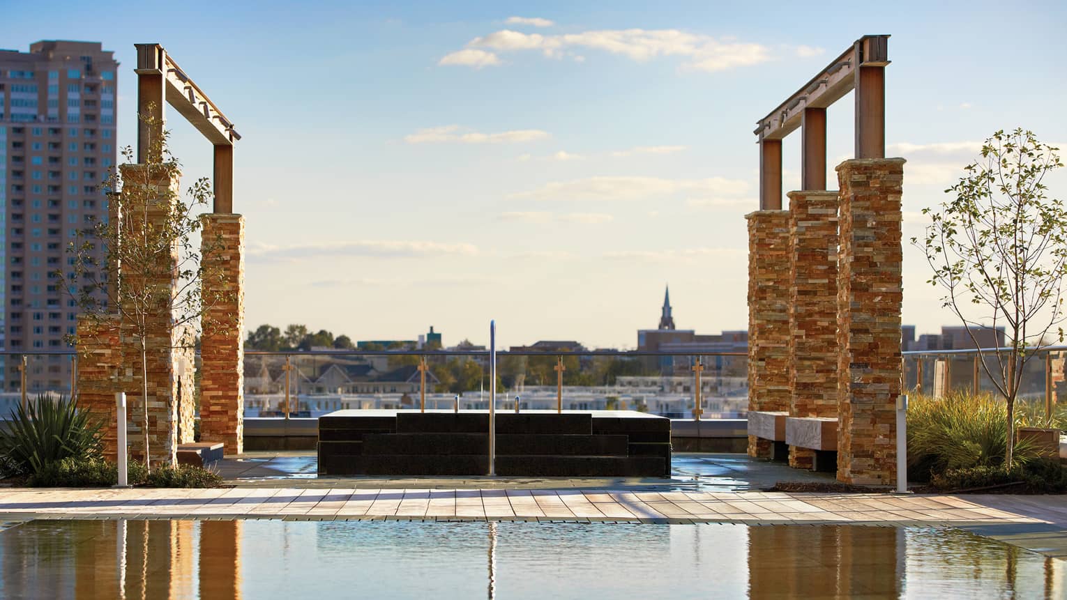 Tall brick pillars, frames over outdoor rooftop whirlpool and reflecting pool