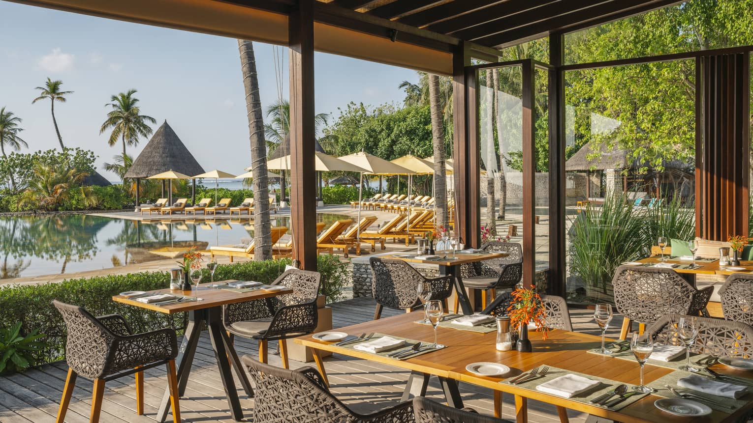 Open-air restaurant Caf� Huraa with rattan chairs and blonde wood tables, overlooking the pool