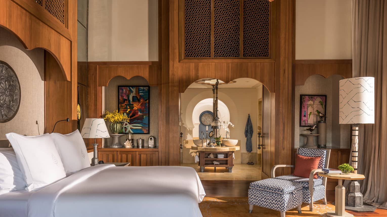 A spacious, sun-lit bedroom with wood finishings and a perfectly-made bed. 