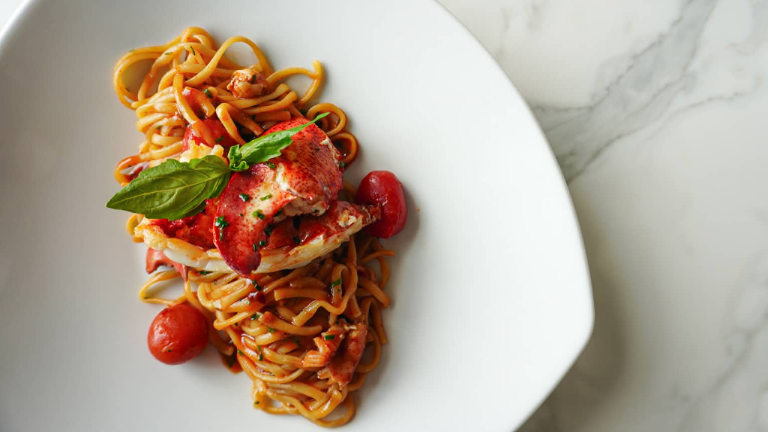 Noodles with red sauce, tomatoes and greens.