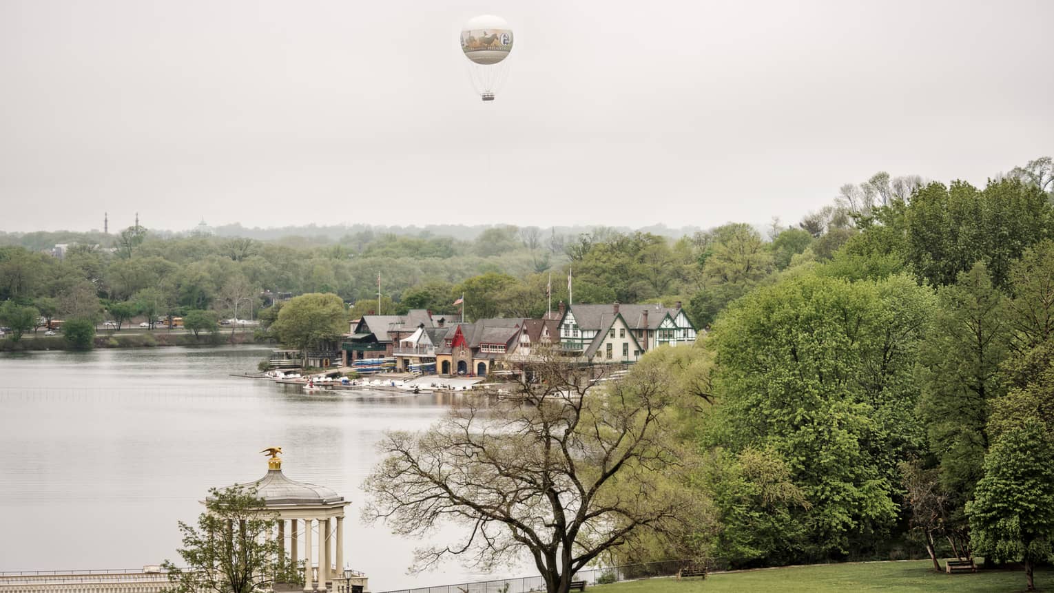 A hot air balloon floating over a body of water with old building on the shore.