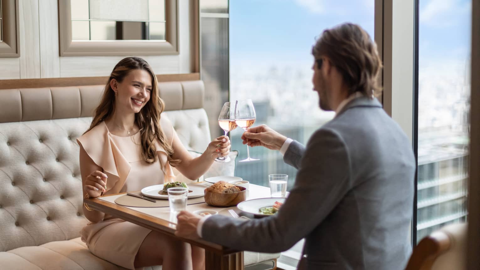 A couple toasts with wine at est, a refined French restaurant in Tokyo, enjoying fine dining with a view.