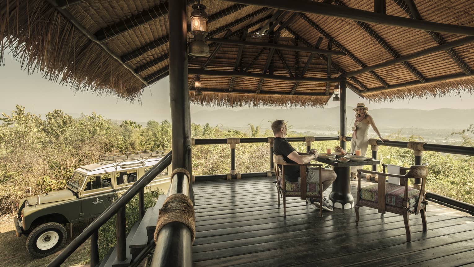 Couple enjoys Camp Peak Breakfast on platform patio near utility vehicle