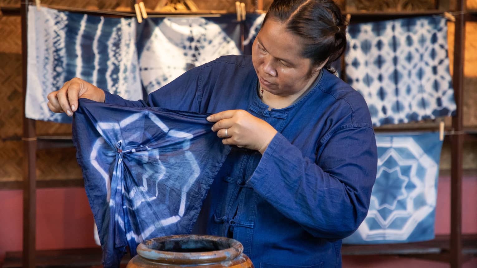 A woman in a blue overshirt, dyeing a piece of fabric.