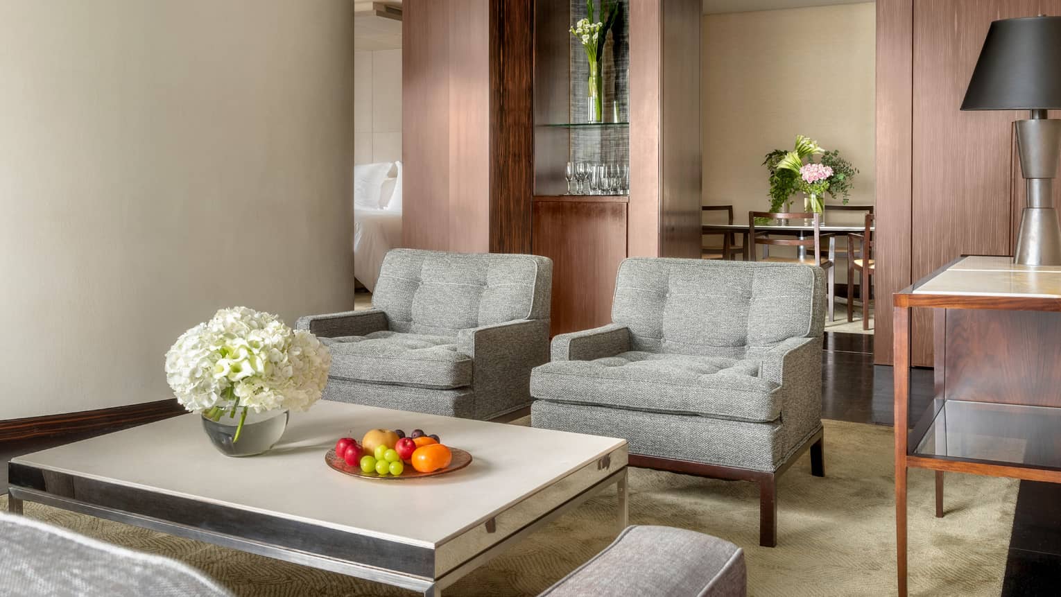 Deluxe One-Bedroom Suite living room vignette with gray club chairs and white coffee table
